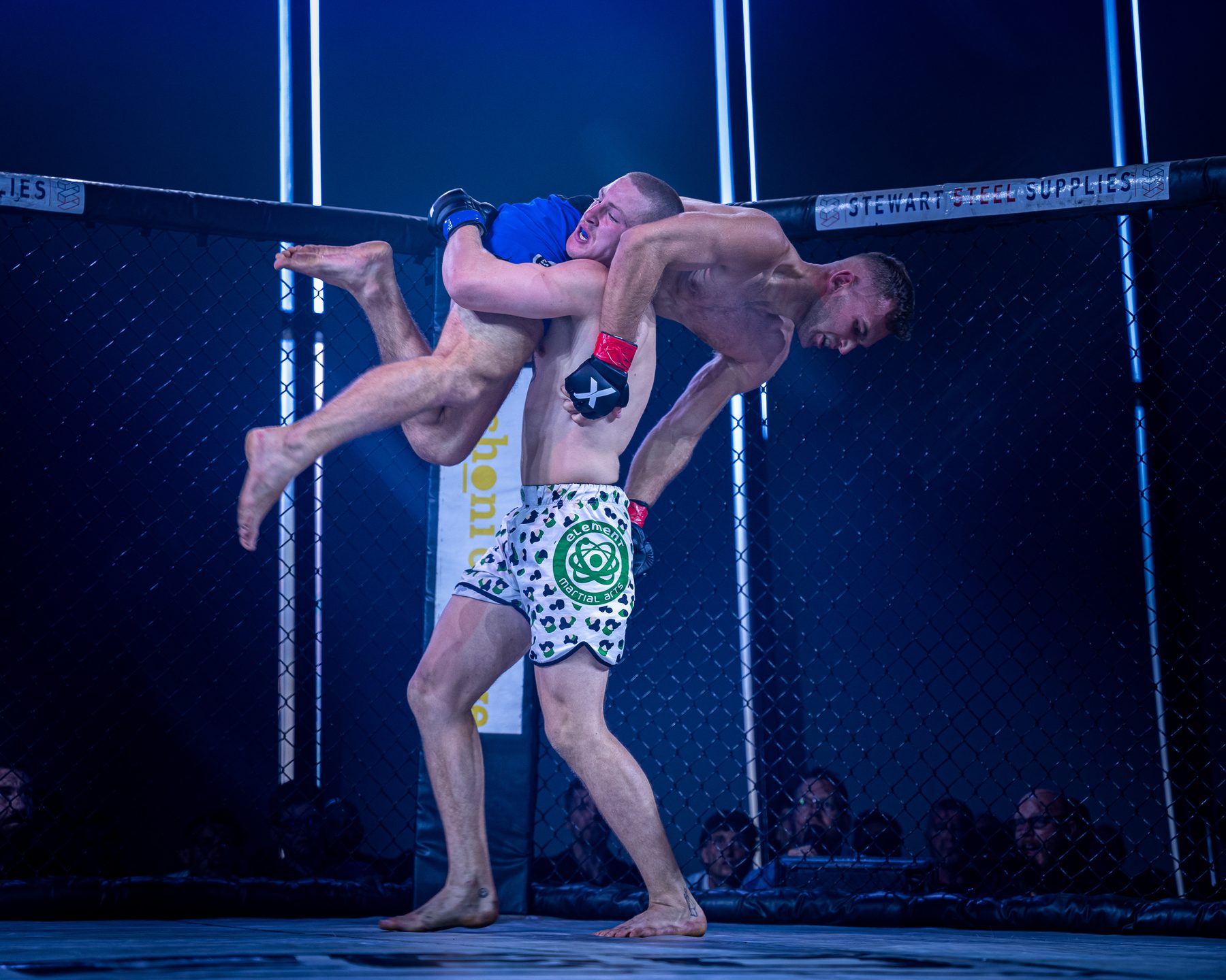 MMA fighter lifting an opponent for a slam during a Loyal Royals-covered cage fight
